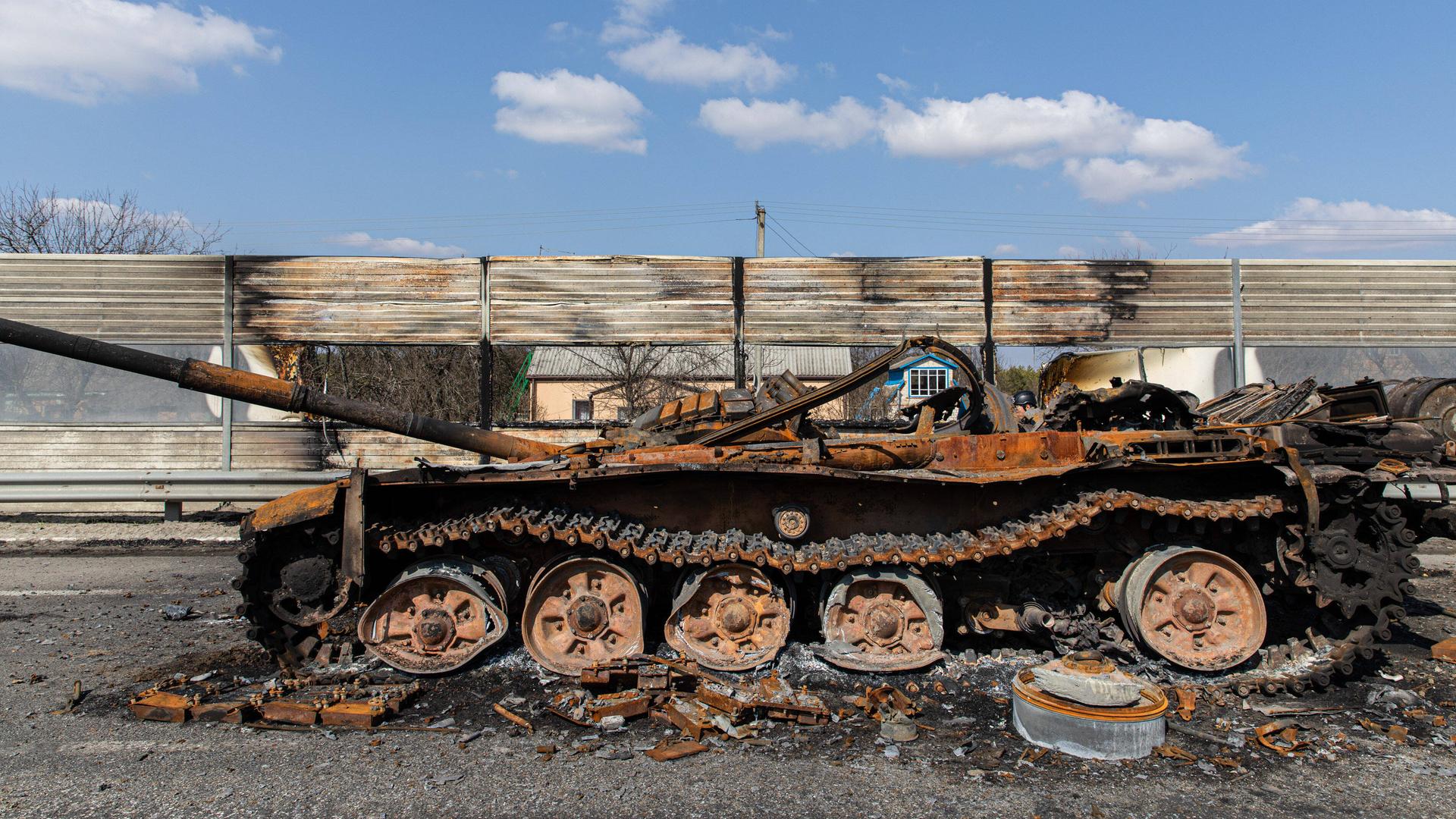 Ein zerstörter, ausgebrannter Panzer auf einer Autobahn