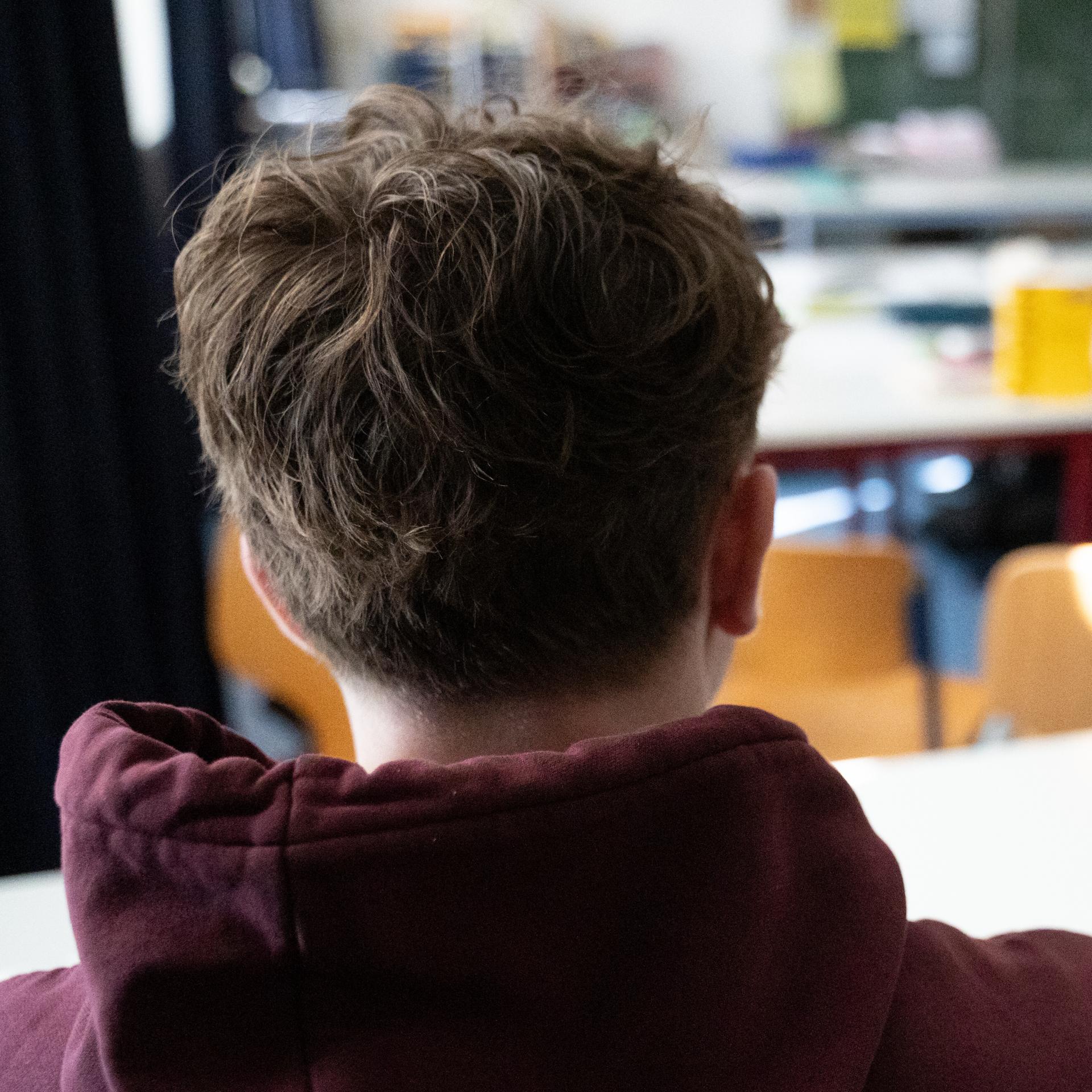 Ein Schüler sitzt an einem Tisch im Klassenzimmer einer Schule.