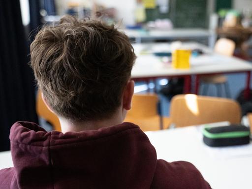 Ein Schüler sitzt an einem Tisch im Klassenzimmer einer Schule.