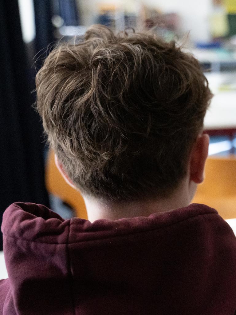 Ein Schüler sitzt an einem Tisch im Klassenzimmer einer Schule.