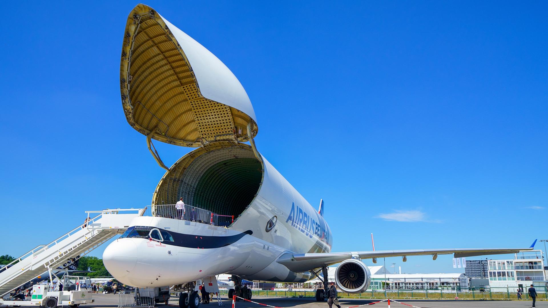 Ein Airbus Beluga XL, eine Variante des Airbus A330 zum Transport von Flugzeugkomponenten zwischen den Airbus-Produktionsstandorten. Der Airbus Beluga XL ist ein zweitstrahliges Transportflugzeug, hier mit geöffnetem Bugtor und angestellter Gangway. Der Himmel im Hintergrund blau.