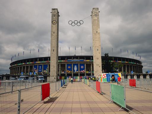 Das Olympiastadion in Berlin von Außen vor grau-bewölktem Himmel.