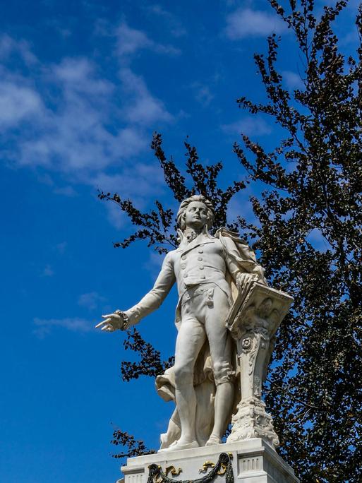Blick auf eine helle Mozart-Statue vor blauem Himmel.