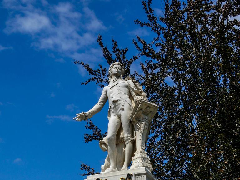 Blick auf eine helle Mozart-Statue vor blauem Himmel.
