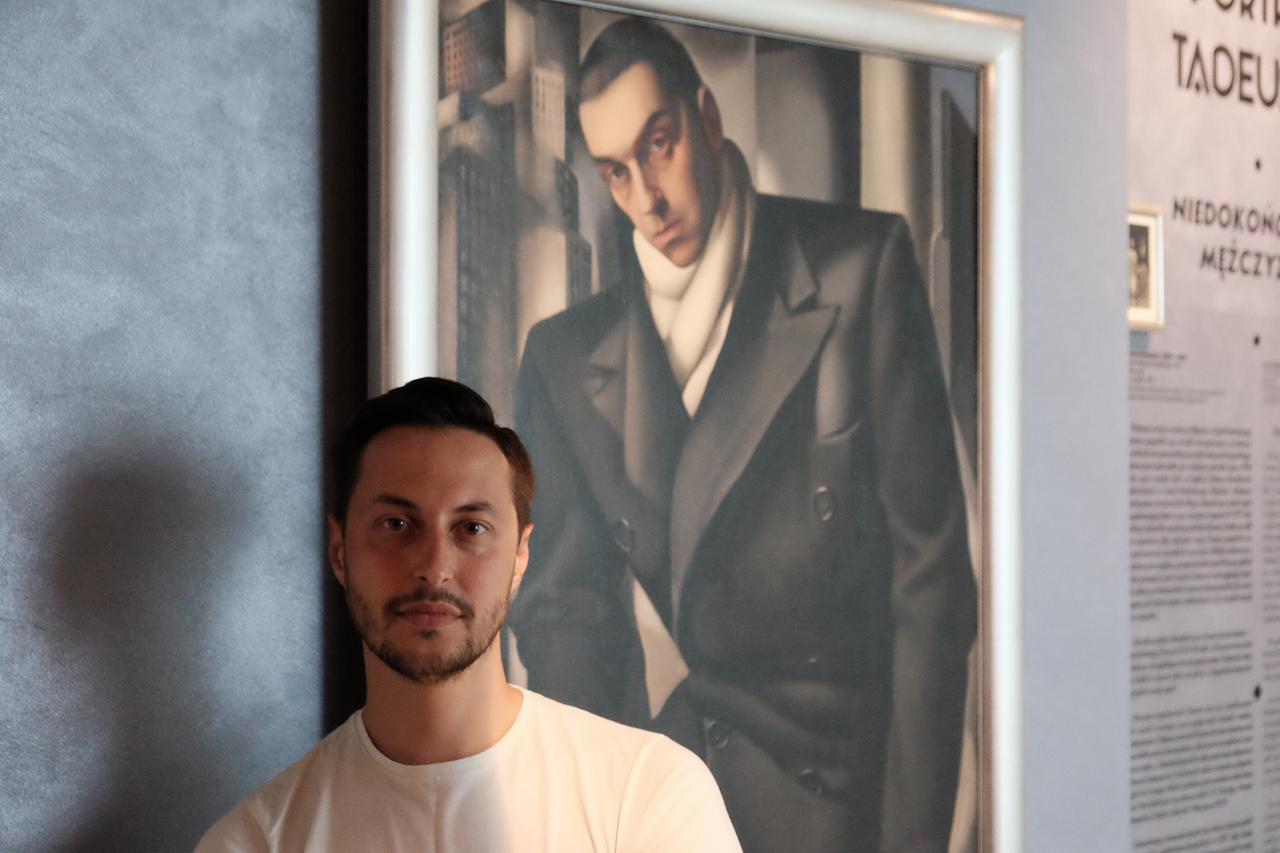 Der Kurator Łukasz Wiącek steht vor Tamaras Lempickas Gemälde „Unvollendetes Porträt eines Mannes“ (1928)