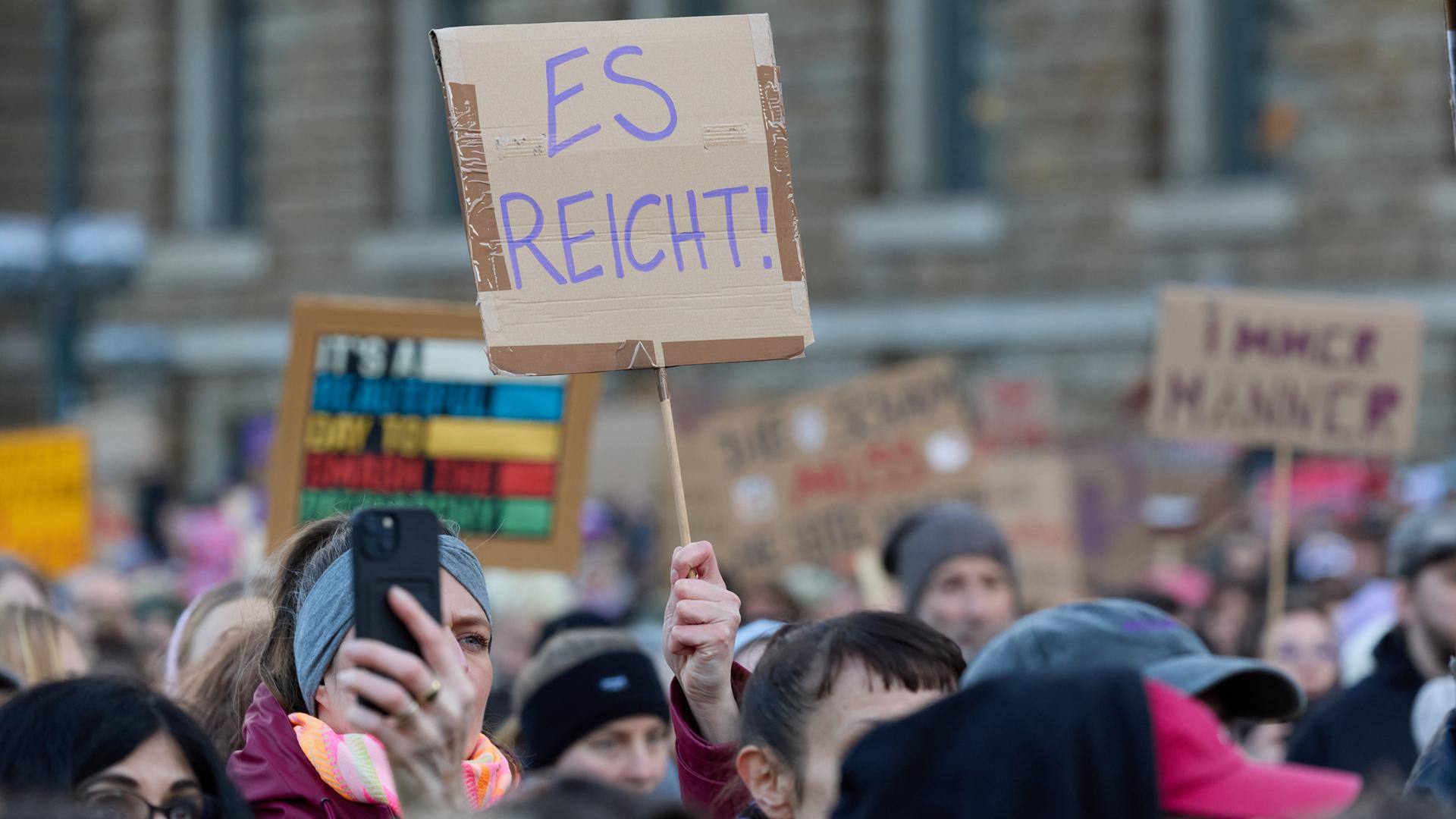 Eine Teilnehmerin hält auf dem Rathausmarkt ein Plakat während der Demonstration gegen sexualisierte Gewalt gegen Frauen hoch.