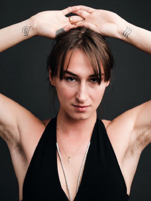 Porträtaufnahme der Schauspielerin Kristina Maca, die die Arme über den Kopf hebt.