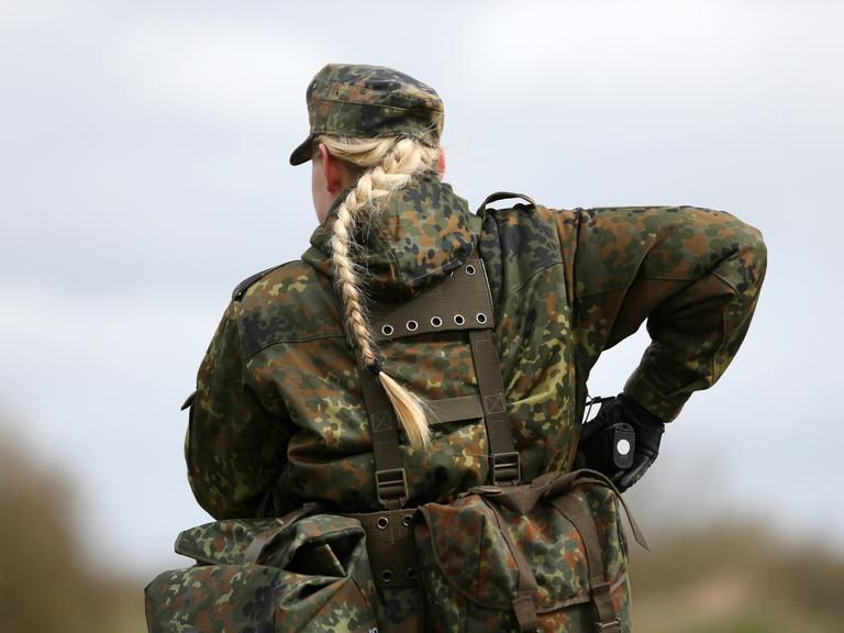 Eine Soldatin der Bundeswehr, sie greift nach ihrer Handfeuerwaffe. 