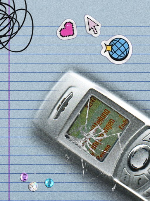 Ein Handy mit zerbrochenem Display liegt auf einem linierten Blatt Papier, daneben ein Herzchen, ein Mauscursor und Glitzersteine