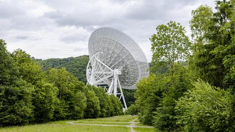 Blick auf das von Grün umgebene Radioteleskop Effelsberg, dessen 100 Meter durchmessender Parabolspiegel die Landschaft prägt.