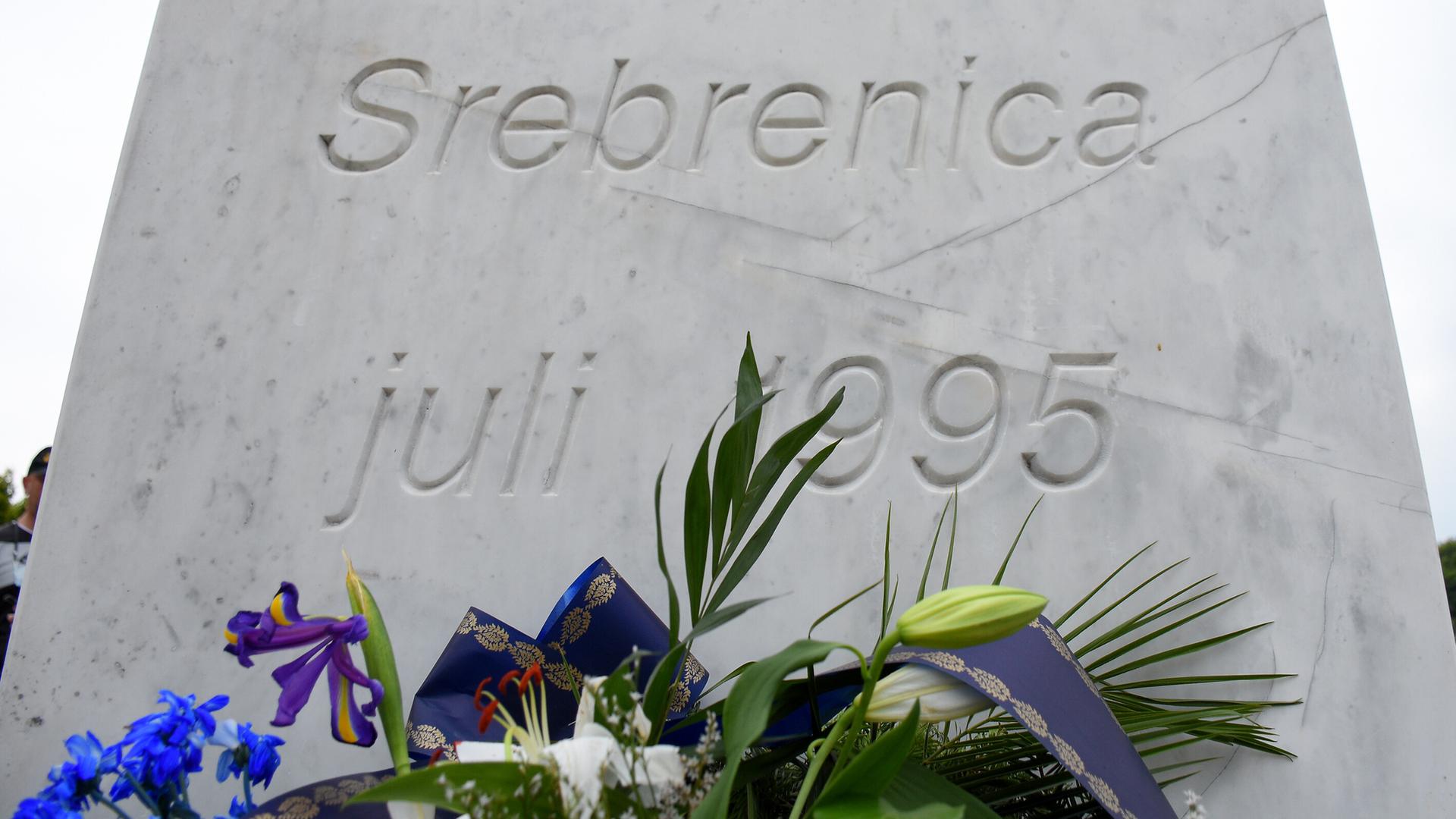 Blick auf einen mit Blumen geschmückten Gedenkstein für die Opfer des Völkermordes von Srebrenica.