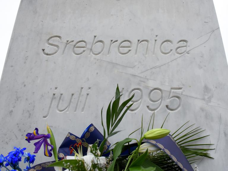 Blick auf einen mit Blumen geschmückten Gedenkstein für die Opfer des Völkermordes von Srebrenica.