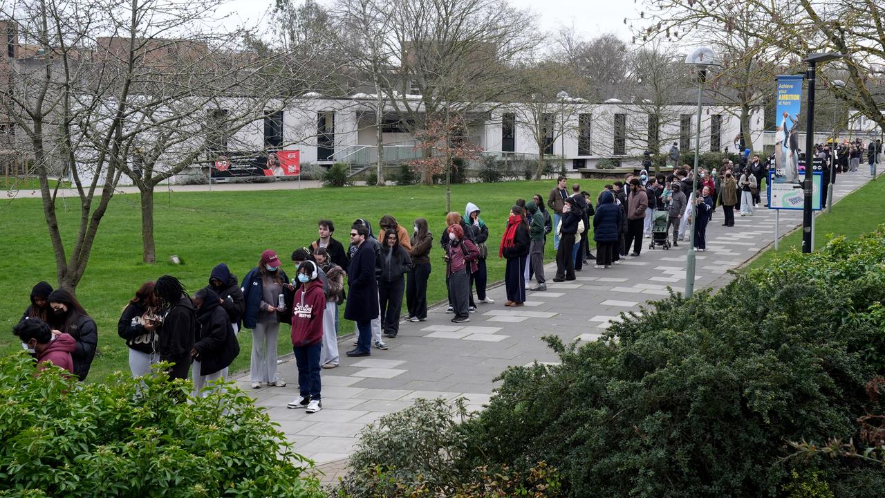 Studenten stehen vor einem Gebäude der Universität von Kent in Canterbury für Antibiotika an. 