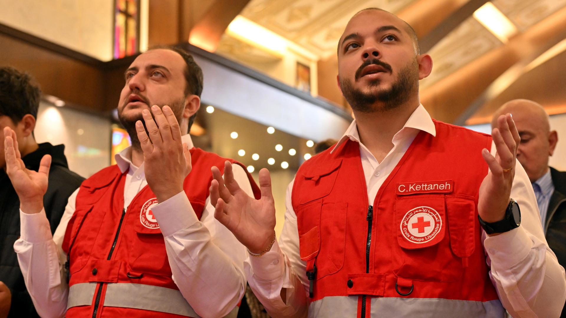 Libanesische Rettungskräfte beten in einer Kirche für fünf Menschen, die bei Angriffen im Norden Beiruts getötet wurden. Die beiden Männer blicken ernst und heben die Hände zum Gebet. Libanesische Rettungskräfte beten in einer Kirche für fünf Menschen, die bei Angriffen im Norden Beiruts getötet wurden. Die beiden Männer blicken ernst und heben die Hände zum Gebet.