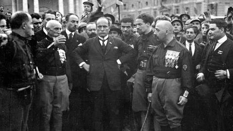 Der Führer der italienischen Faschisten, Benito Mussolini (M), posiert am 29. Oktober 1922 inmitten einiger seiner in schwarze Hemden gekleideter Gefolgsleute. Am Vortag, dem 28. Okotber 1922, waren rund 15000 faschistische "Schwarzhemden", die sich von dem geringen Widerstand der Bevölkerung überrascht zeigten, in Rom einmarschiert. Mit dem "Marsch auf Rom" erzwang Mussolini seine Ernennung zum Ministerpräsidenten.