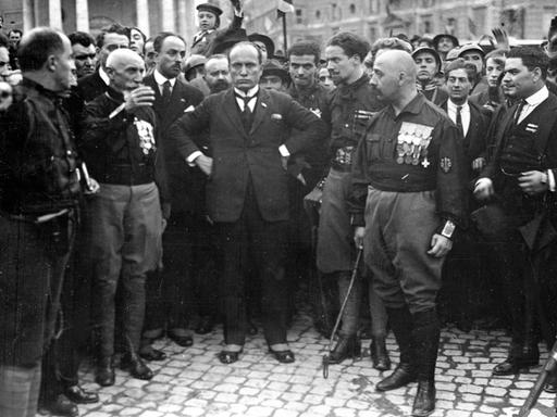 Der Führer der italienischen Faschisten, Benito Mussolini (M), posiert am 29. Oktober 1922 inmitten einiger seiner in schwarze Hemden gekleideter Gefolgsleute. Am Vortag, dem 28. Okotber 1922, waren rund 15000 faschistische "Schwarzhemden", die sich von dem geringen Widerstand der Bevölkerung überrascht zeigten, in Rom einmarschiert. Mit dem "Marsch auf Rom" erzwang Mussolini seine Ernennung zum Ministerpräsidenten.