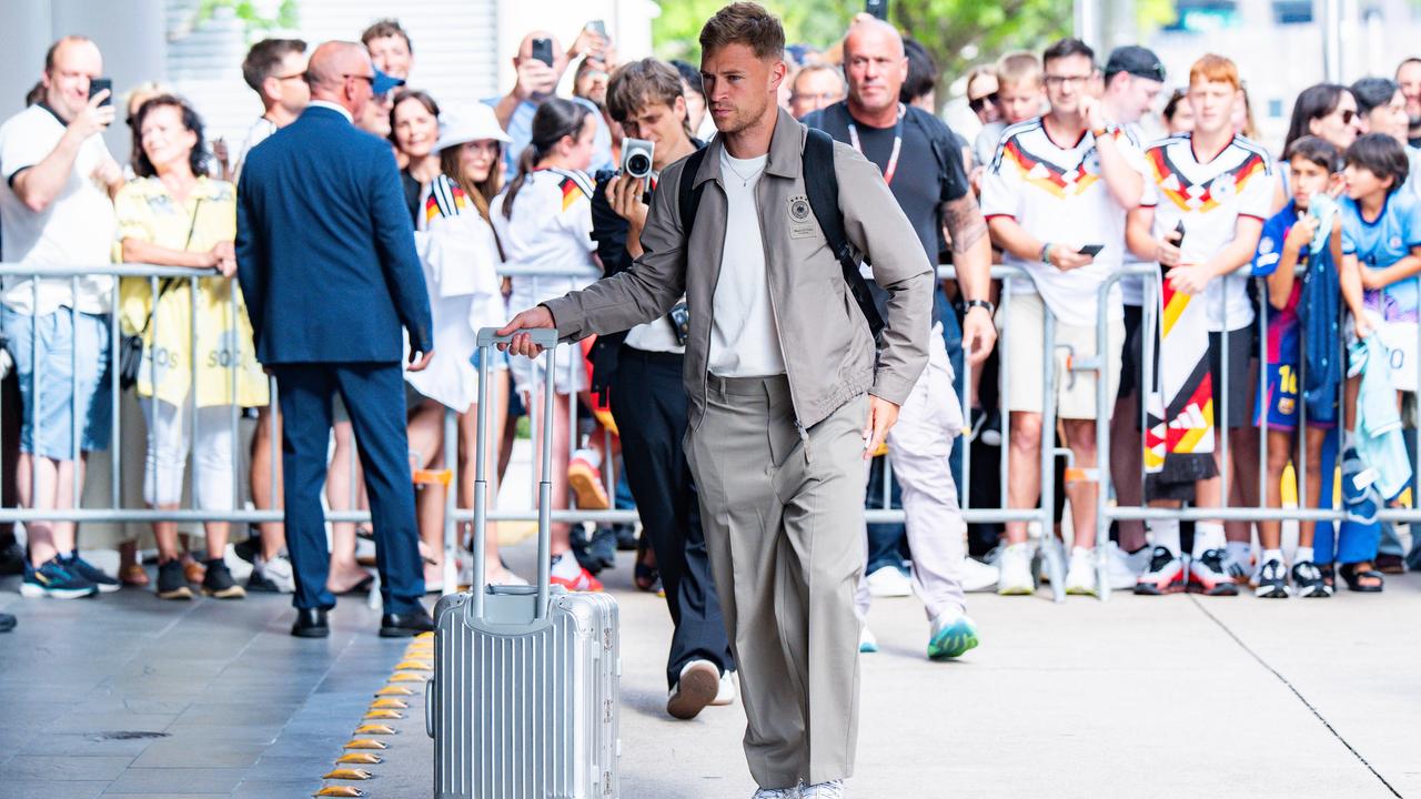 Joshua Kimmich kommt mit einem Rollkoffer am Team-Hotel der deutschen Mannschaft in Houston an, im Hintergrund Fans im DFB-Trikot.