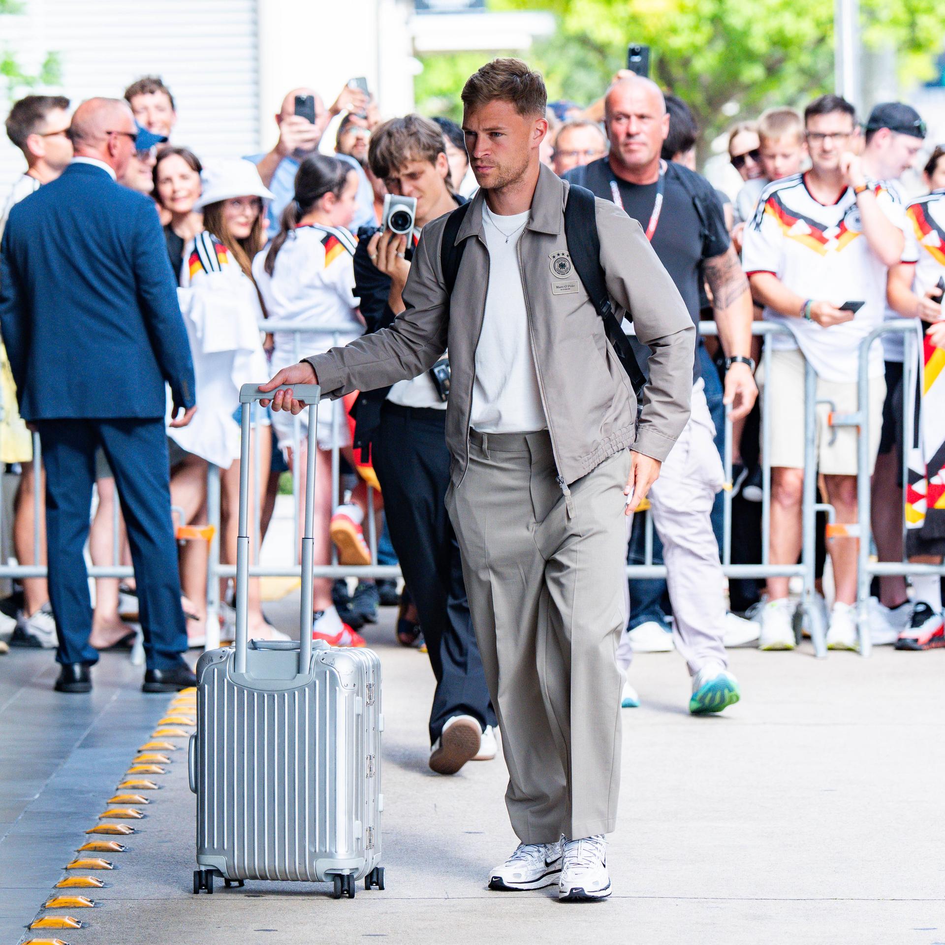 Joshua Kimmich kommt mit einem Rollkoffer am Team-Hotel der deutschen Mannschaft in Houston an, im Hintergrund Fans im DFB-Trikot.