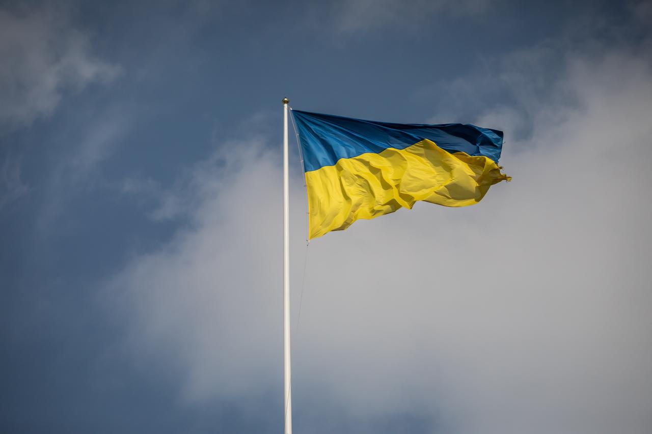 Eine ukrainische Fahne flattert in Kiew im Wind, im Hintergrund blauer Himmel