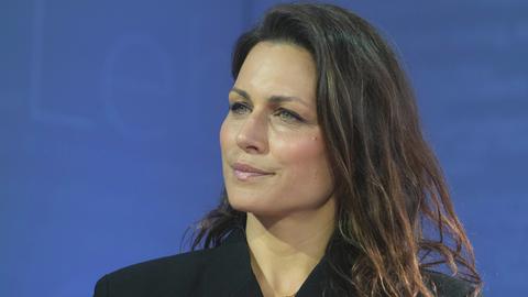 Porträt der Publizistin Shila Behjat vor blauem Hintergrund.