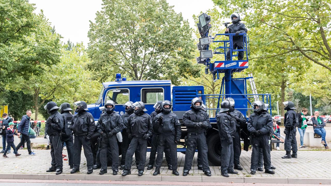 Vor dem Weserstadion in Bremen stehen Polizeikräfte in Schutzkleidung.