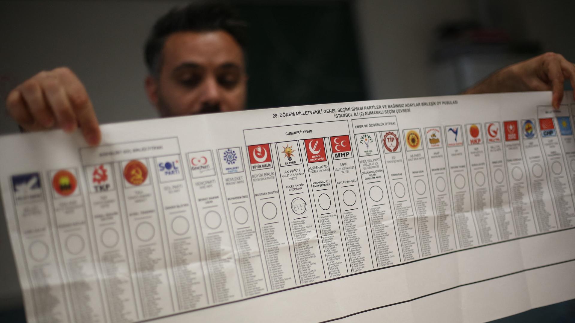 Ein Mann hält einen Stimmzettel der Wahl am 14. Mai in die Höhe. Darauf sind die Symbole der Parteien, die zur Abstimmung standen.
