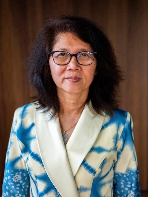 Die Schriftstellerin Ma Thida trägt eine Brille und ein blau-weißes Batik-Jackett.