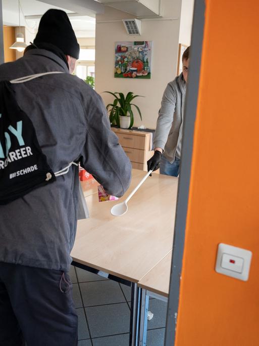 Ein junger Mann arbeitet als Freiwilliger in der Obdachlosentagesstätte Olga 46.Er reicht einem Mann ein Getränk und etwas zu essen. Das Foto ist von 2020. Ein junger Mann arbeitet als Freiwilliger in der Obdachlosentagesstätte Olga 46.Er reicht einem Mann ein Getränk und etwas zu essen. Das Foto ist von 2020.