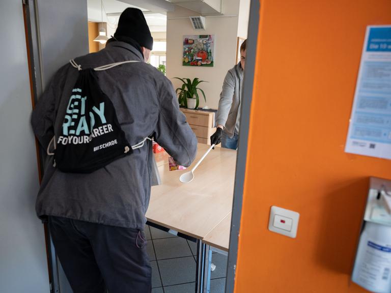 Ein junger Mann arbeitet als Freiwilliger in der Obdachlosentagesstätte Olga 46.Er reicht einem Mann ein Getränk und etwas zu essen. Das Foto ist von 2020. Ein junger Mann arbeitet als Freiwilliger in der Obdachlosentagesstätte Olga 46.Er reicht einem Mann ein Getränk und etwas zu essen. Das Foto ist von 2020.