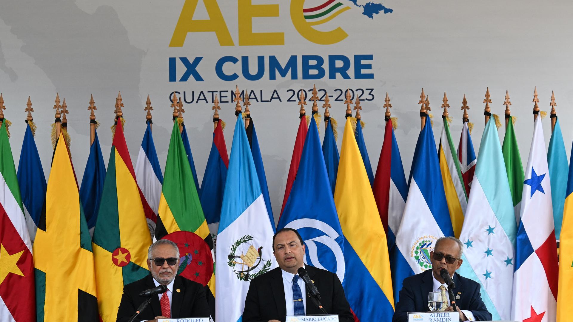 Konferenz des Verbands der Karibischen Staaten: Generalsekretär Sabonge, Guatemalas Außenminister Bucaro und der Außenminister von Surinam, Ramdin sitzen an einem Tisch vor den Flaggen der Mitgliedsstaaten.