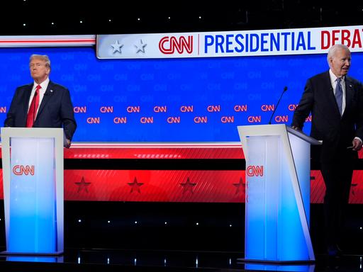 Donald Trump und Joe Biden in einem Fernseh-Studio. Beide stehen an einem Redner-Pult. Joe Biden dreht sich weg.
