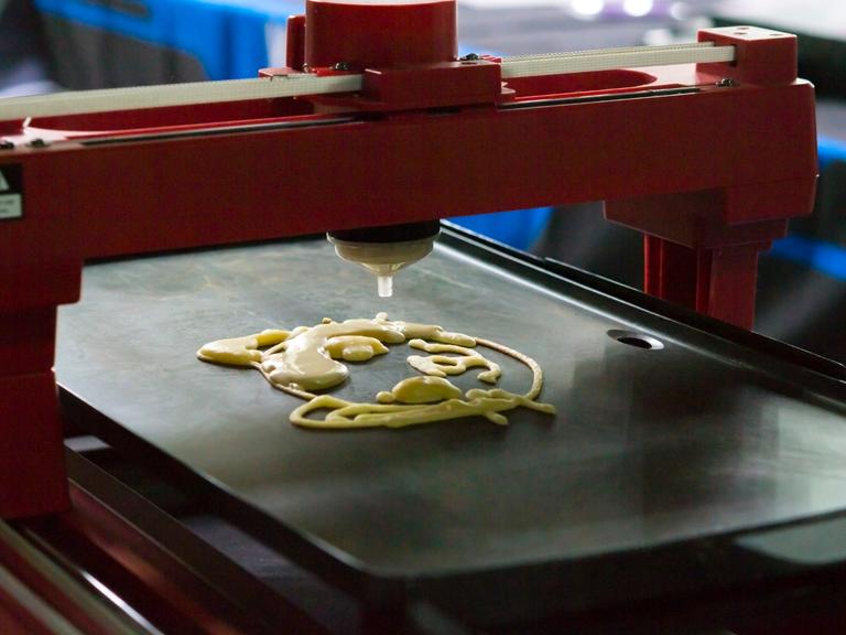 Ein 3D-Drucker druckt flüssigen Teig auf ein Blech.