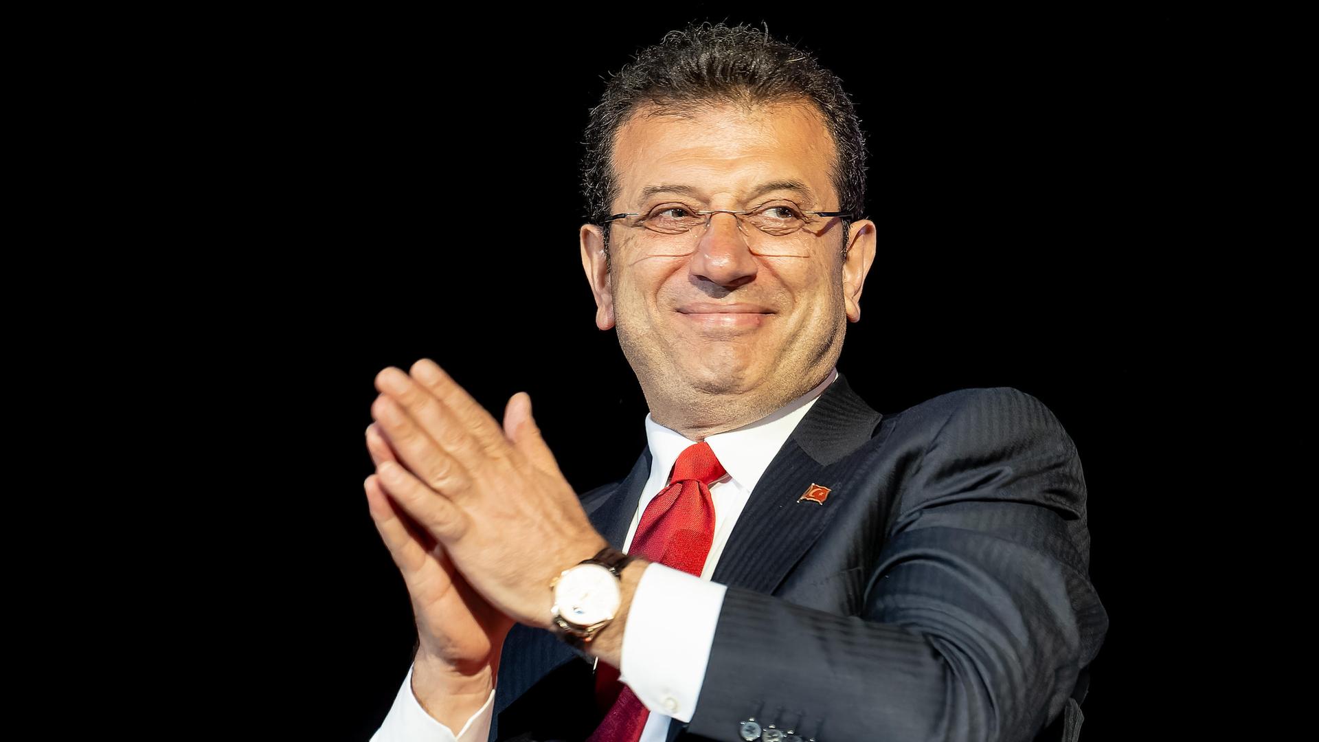 Der türkische Politiker Ekrem Imamoglu von der CHP lächelt von einer Tribüne herab