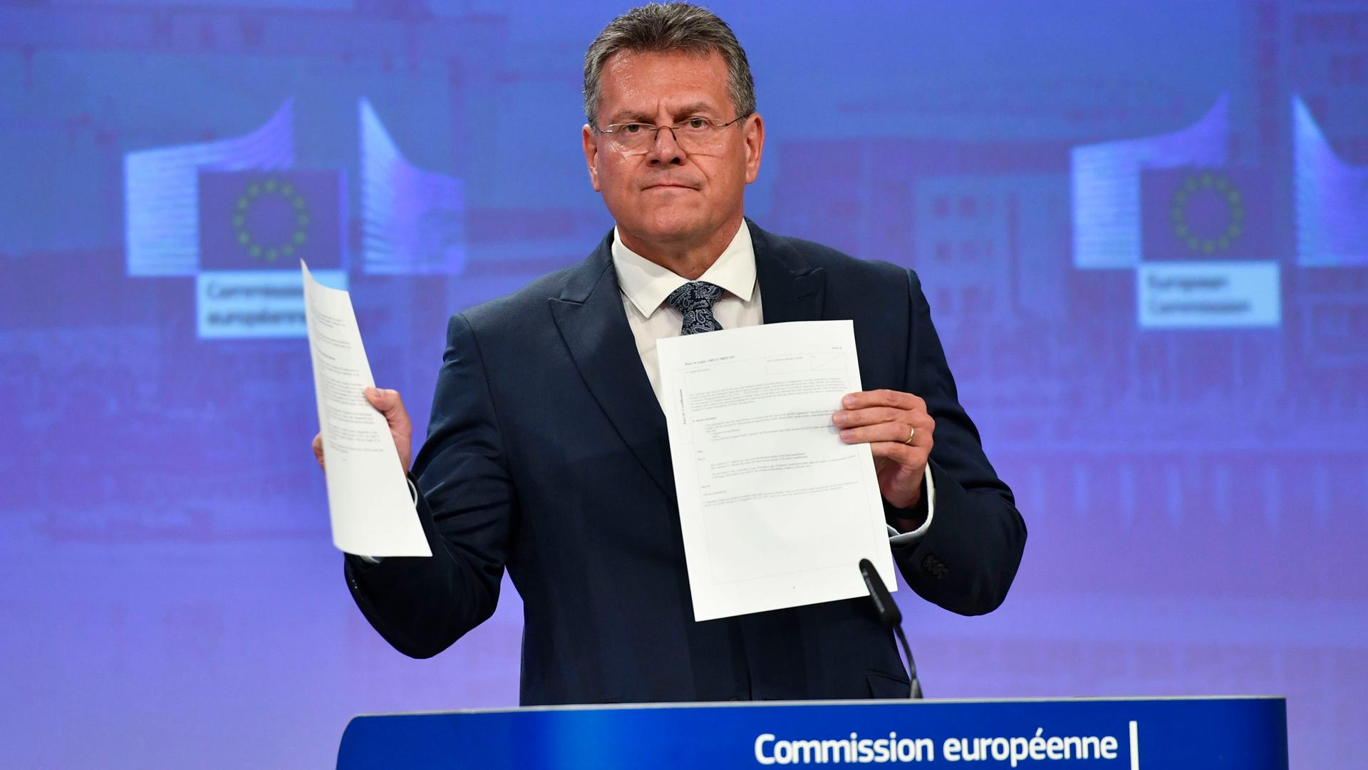 EU-Kommissar Maros Sefcovic steht hinter einem Rednerpult und hält ein Dokument hoch.