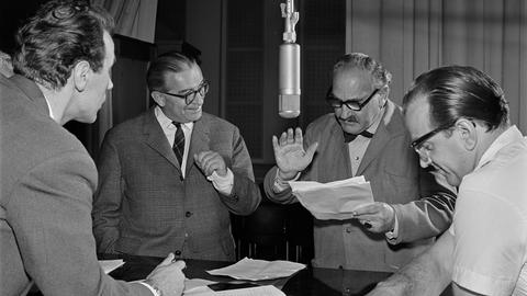 Die Science Fiction Hörspiel-Serie "Unternehmen Luna" wird im RIAS Radio im Jahr 1960 aufgenommen. Vier Schauspieler stehen um ein Mikrofon mit Textzetteln in der Hand.