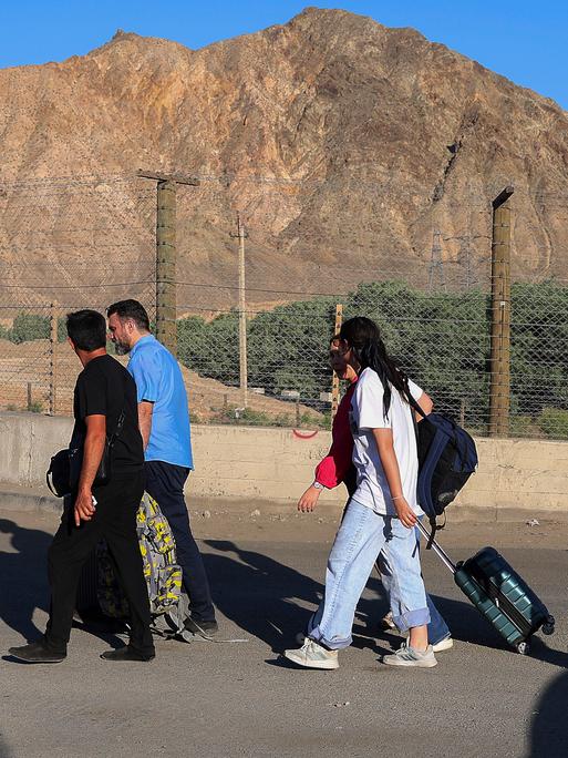 Menschen, überwiegend Iranerinnen und Iraner, die ihr Land aufgrund israelischer Angriffe verlassen haben, gehen über den Grenzübergang in der Nähe des Dorfes Agarak im Süden Armeniens. 