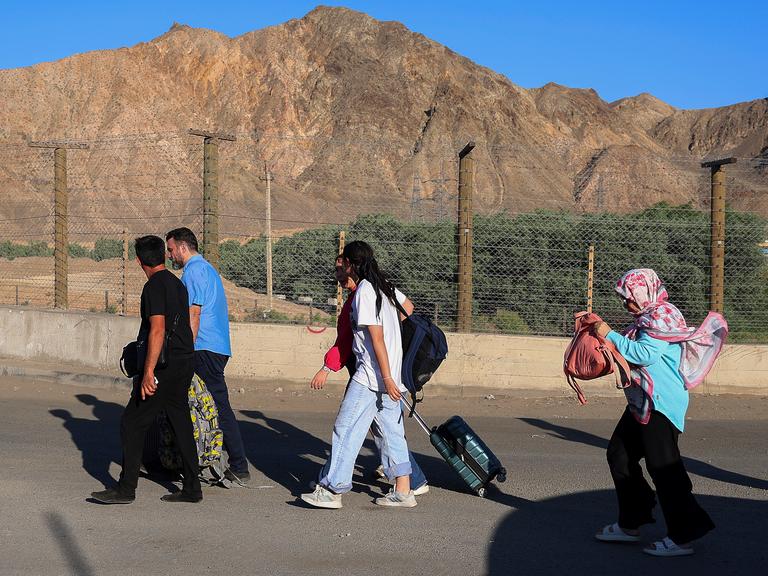 Menschen, überwiegend Iranerinnen und Iraner, die ihr Land aufgrund israelischer Angriffe verlassen haben, gehen über den Grenzübergang in der Nähe des Dorfes Agarak im Süden Armeniens. 