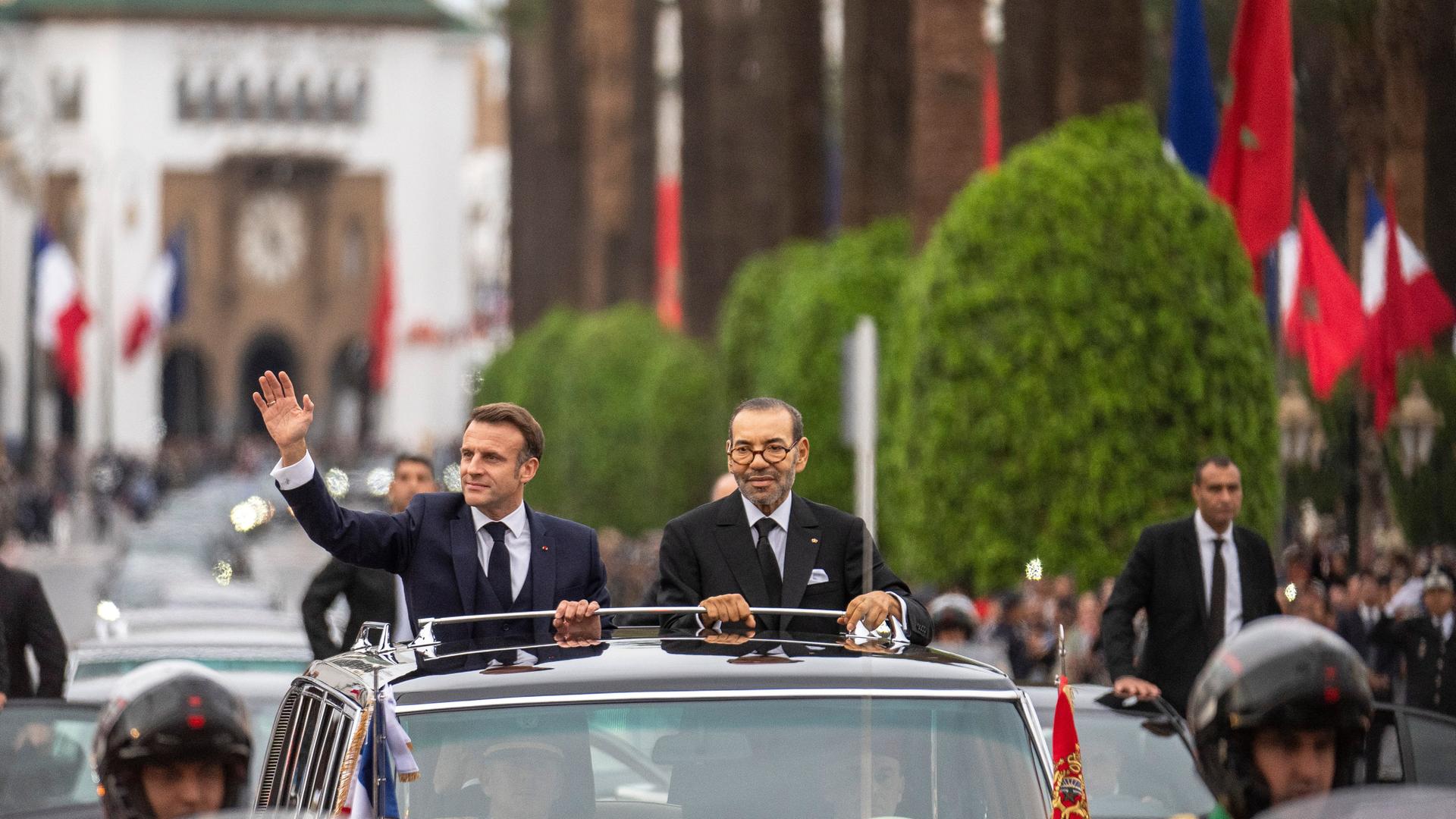 Der französische Präsident Macron fährt neben dem marokkanischen König Mohammed VI in einem offenen Wagen durch Rabat.