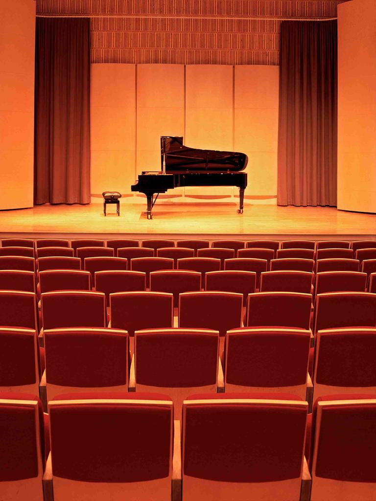 Ein leerer Konzertsaal. Auf der Bühne steht ein Flügel mit Hocker davor.