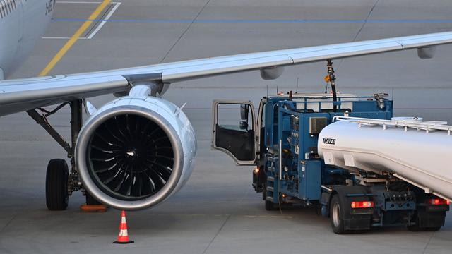 Von dem Flugzeug sieht man nur einen Flügel mit einer großen Turbine. Daneben steht das Tankfahrzeug, aus dem ein Schlauch mit der Tanköffnung im Flügel verbunden ist. 