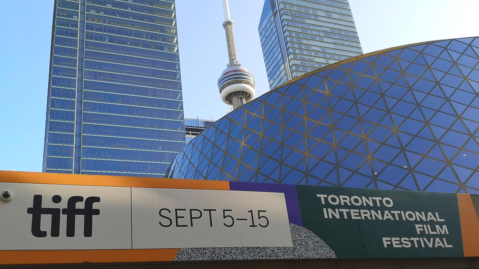 Ein Plakat an einer Wand vor einem modernen Gebäude weist auf das Filmfestival in Toronto hin.