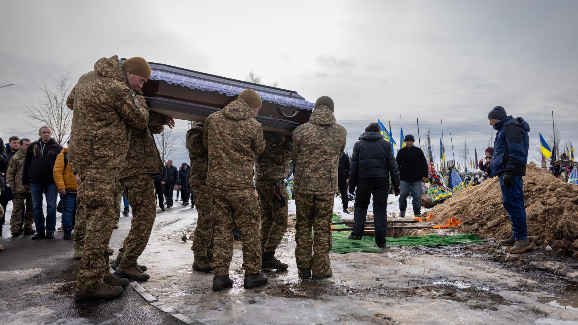 Auf einem Friedhof in Bucha tragen Angehörige und Soldaten während einer Beerdigung den Sarg eines gefallenen ukrainischen Soldaten