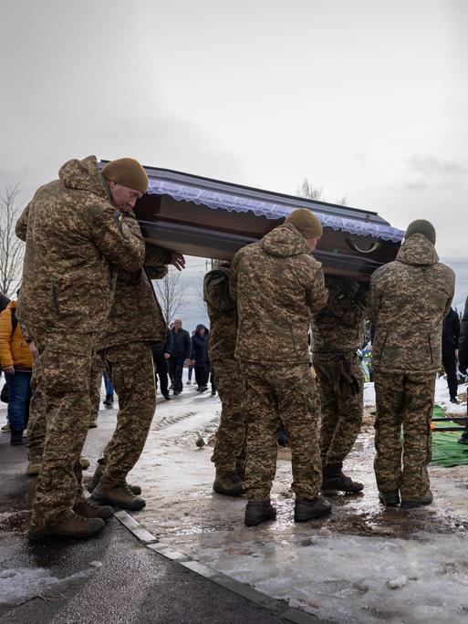 Auf einem Friedhof in Bucha tragen Angehörige und Soldaten während einer Beerdigung den Sarg eines gefallenen ukrainischen Soldaten