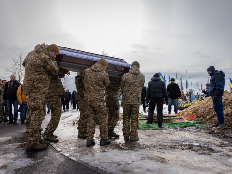 Auf einem Friedhof in Bucha tragen Angehörige und Soldaten während einer Beerdigung den Sarg eines gefallenen ukrainischen Soldaten