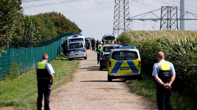 Polizisten durchsuchen Felder. Im Hintergrund sind Strom-Masten zu sehen.