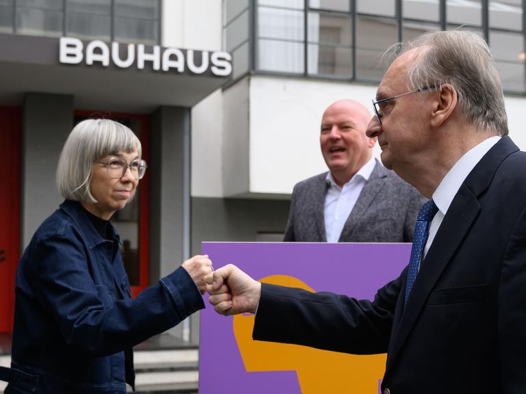 Barbara Steiner, Direktorin der Stiftung Bauhaus Dessau, und Reiner Haseloff (CDU, r), Ministerpräsident von Sachsen-Anhalt, stehen vor dem Bauhausgebäude in Dessau. Vor 100 Jahren zog das Bauhaus von Weimar nach Dessau. 
