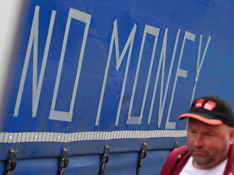 Roman Koval aus Lemberg (Ukraine) geht an einem Anhänger vorbei, auf dessen Plane die Worte "No Money" mit Klebeband aufgeklebt sind.