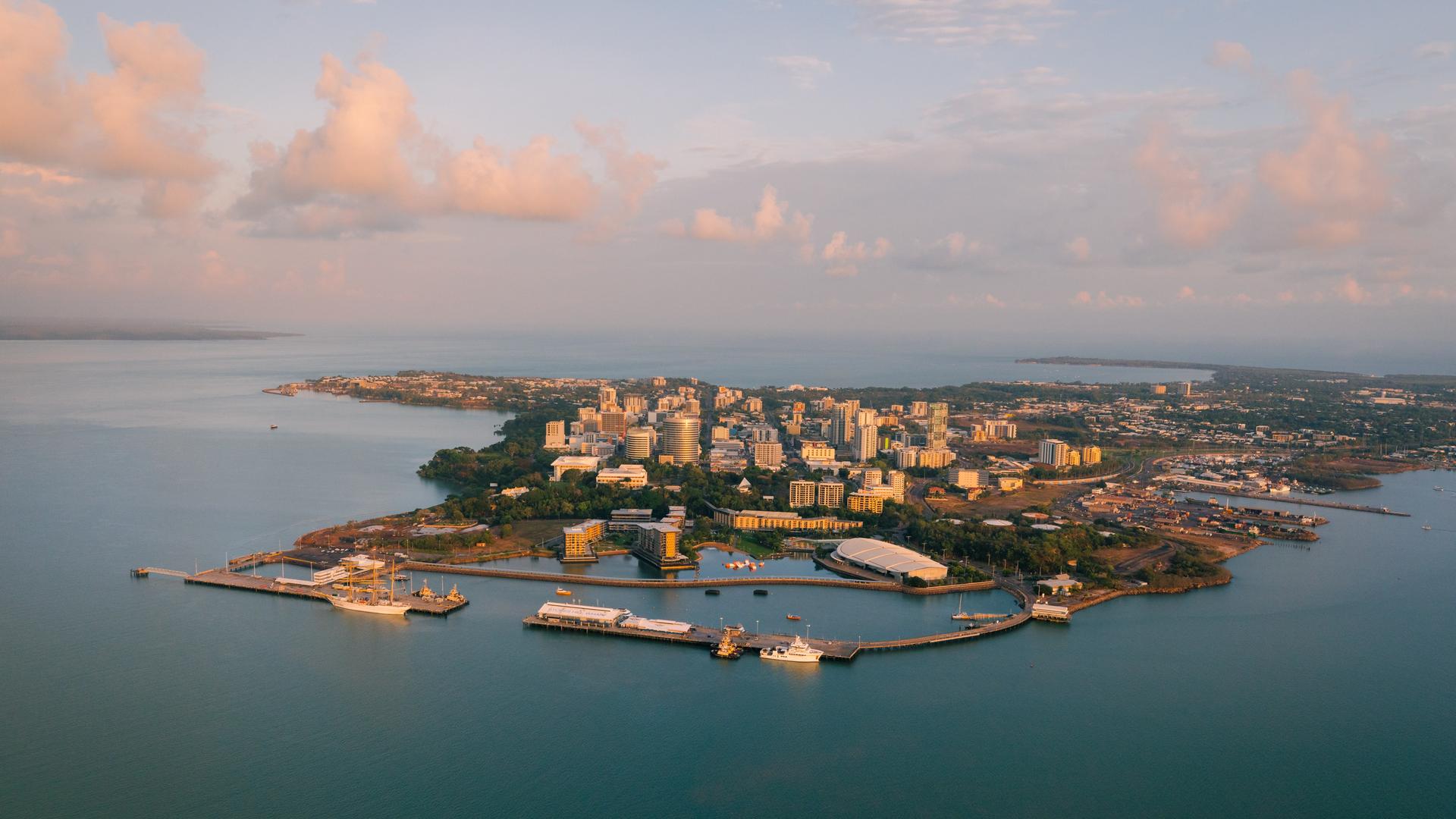 Luftaufnahme der Stadt Darwin mit vorgelagertem Hafen im Sonnenaufgang.