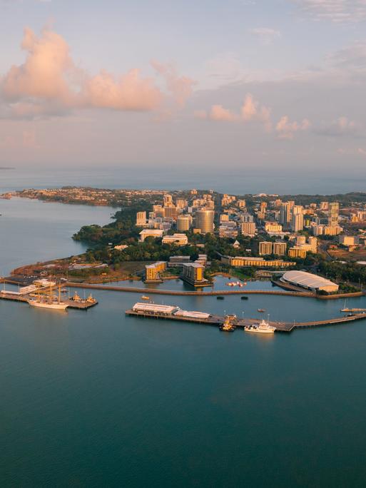 Luftaufnahme der Stadt Darwin mit vorgelagertem Hafen im Sonnenaufgang.