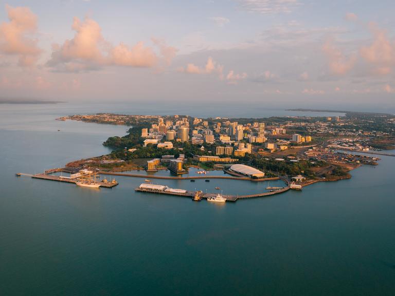 Luftaufnahme der Stadt Darwin mit vorgelagertem Hafen im Sonnenaufgang.